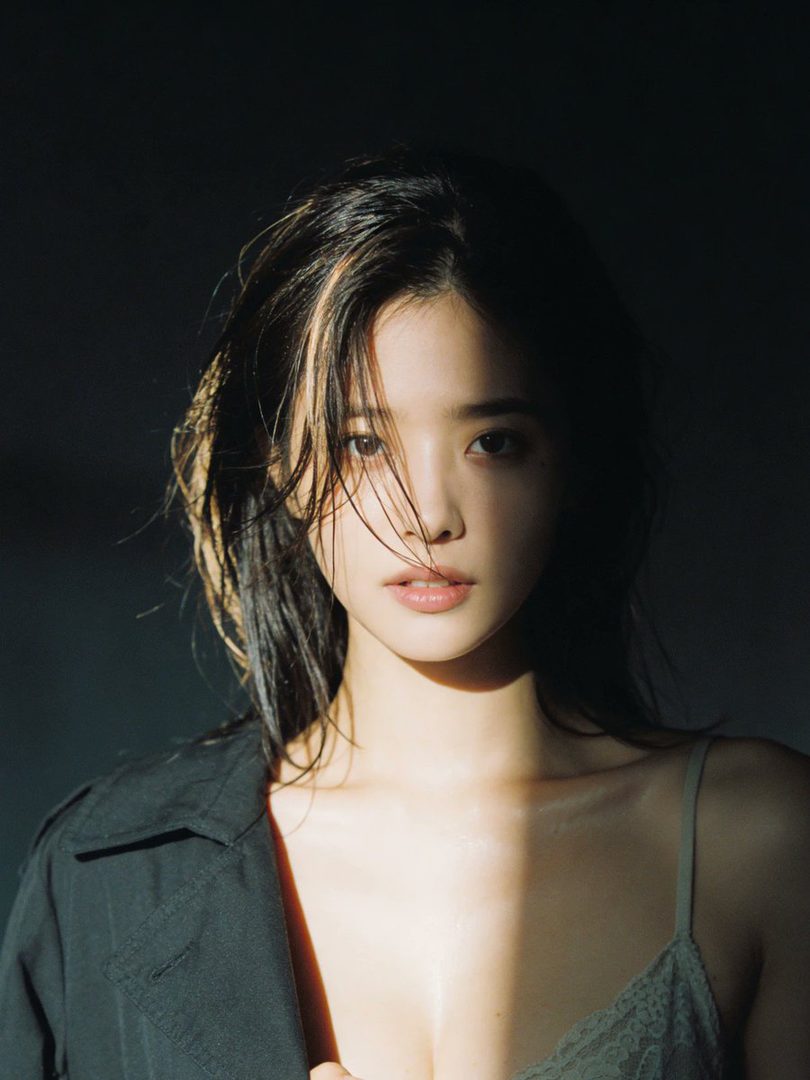 A photorealistic portrait of a woman with wet brown hair and a black jacket, with strong light and shadow contrast.