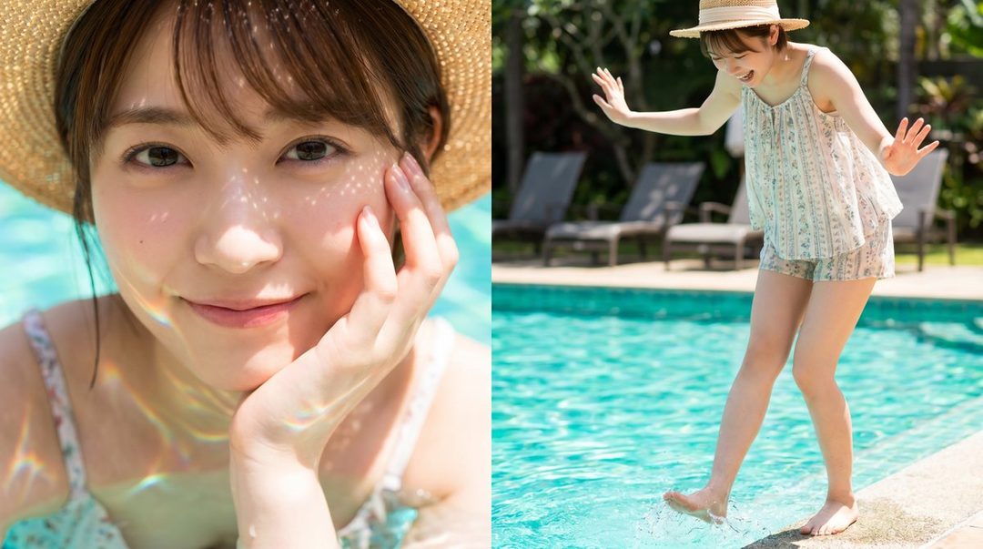 A young woman in a straw hat and casual top smiles playfully by a swimming pool on a sunny day.