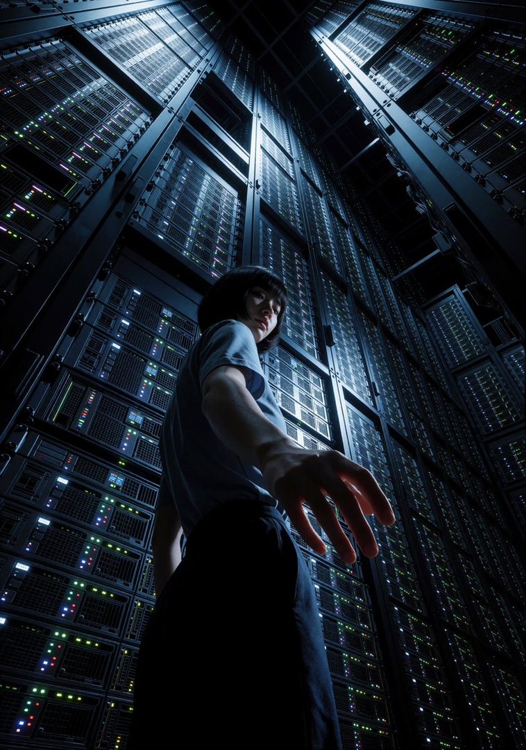 A woman with short black hair stands in a server room, reaching out with one hand, surrounded by glowing server racks.