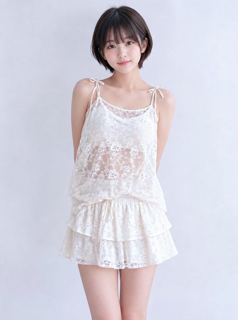 A young woman with short brown hair and bangs poses in a white lace camisole and matching tiered skirt against a plain white background.