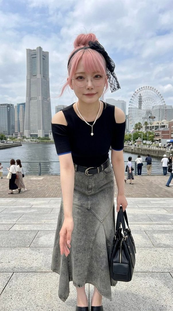A young woman with pink hair, glasses, and a black off-shoulder top poses in front of a city skyline with a ferris wheel and a body of water.