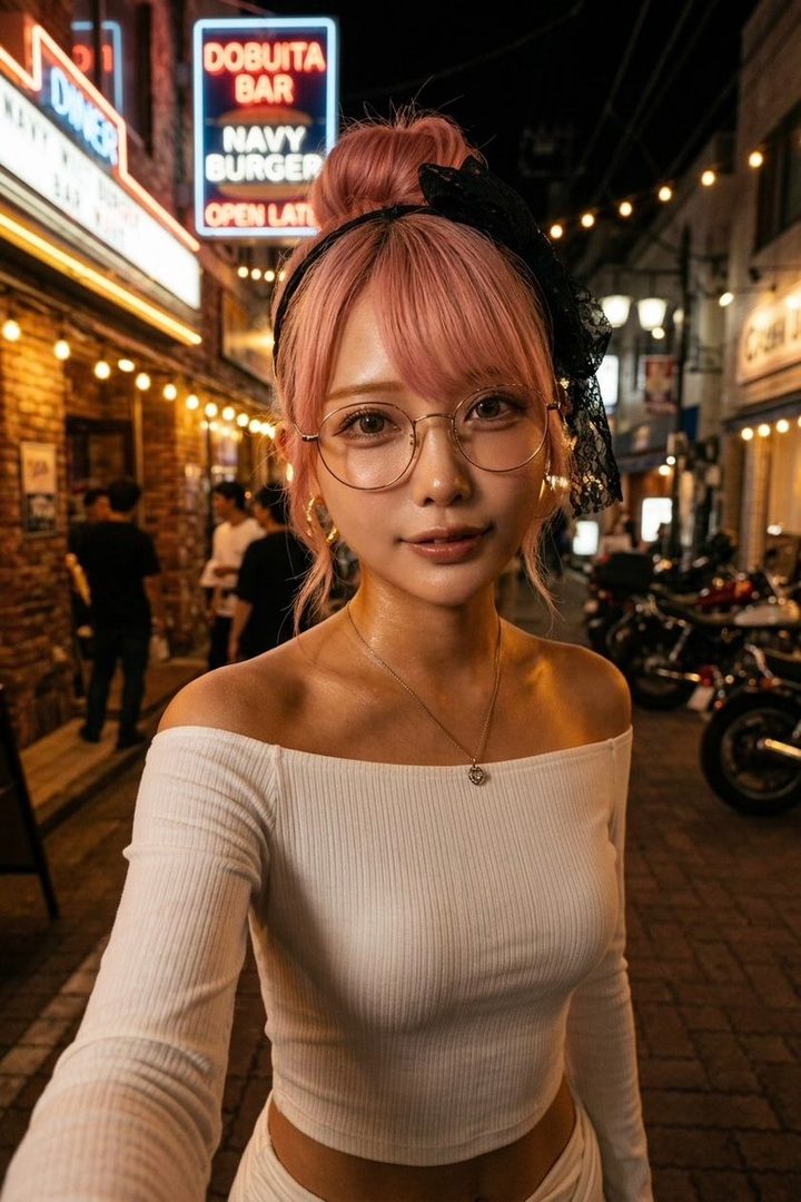 A young woman with pink hair, glasses, and an off-shoulder top takes a selfie on a city street at night, with neon signs in the background.