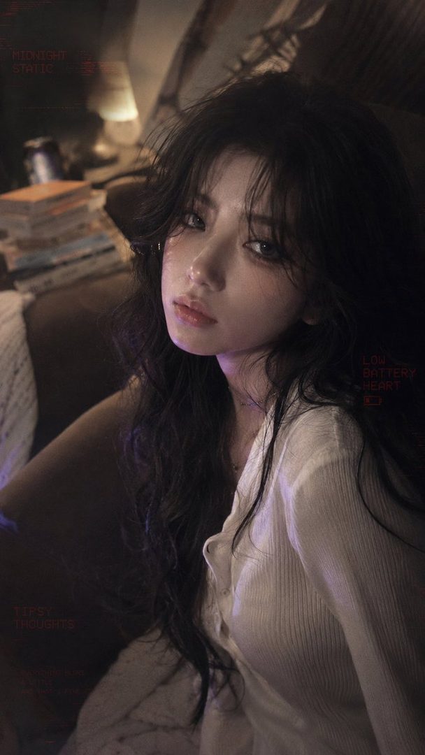 A photorealistic portrait of a young woman with long dark hair and a white blouse, looking directly at the viewer in a dimly lit indoor setting.