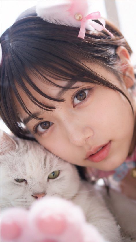 A cute East Asian woman with brown hair and bangs, wearing cat ears, poses closely with a white cat.