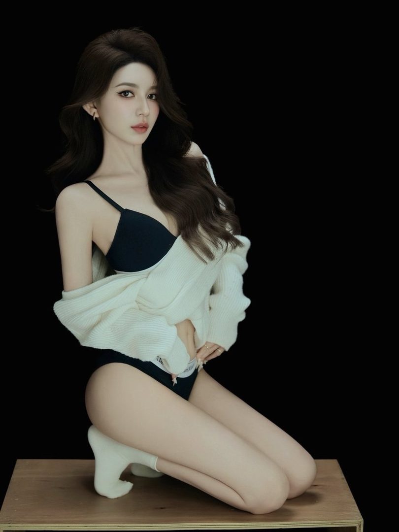 A photorealistic portrait of an East Asian woman with long brown hair, wearing a black bra and underwear with a white knit cardigan, kneeling on a wooden surface against a black background.