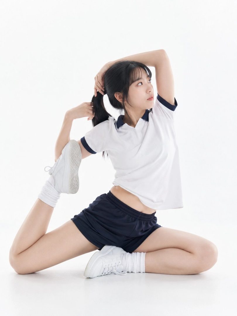 A young East Asian woman in sportswear is stretching on a white studio floor, looking upwards with a focused expression.