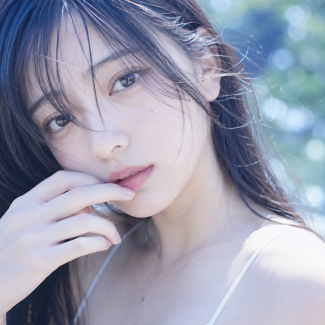 A photorealistic portrait of a young woman with long dark hair and bangs, looking directly at the viewer with a dreamy expression.