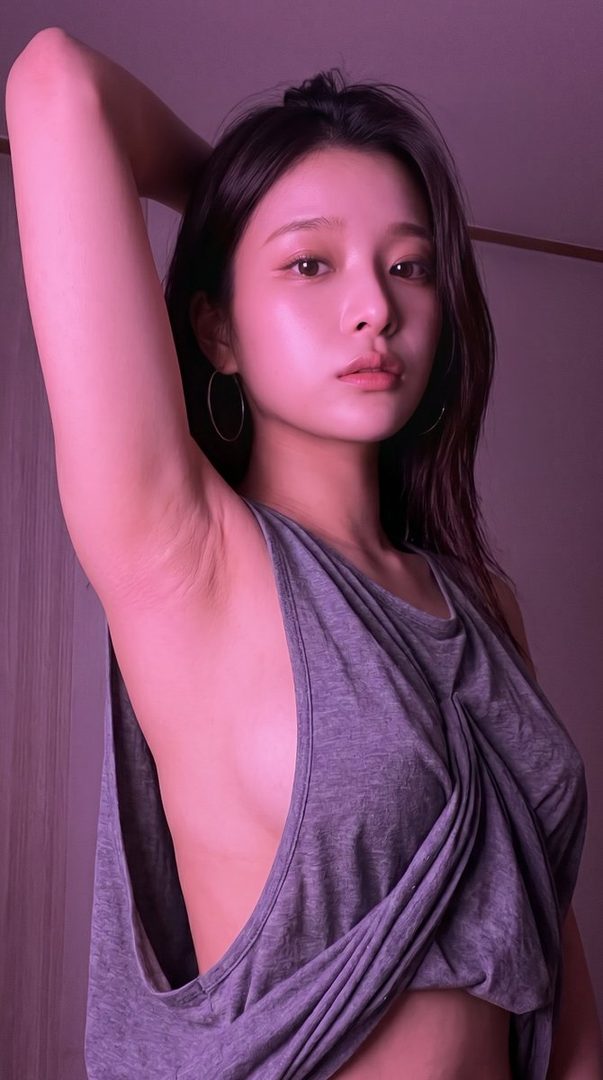 A photorealistic portrait of a young East Asian woman with long black hair, wearing a grey tank top, posing indoors with her arm raised, under purple lighting.