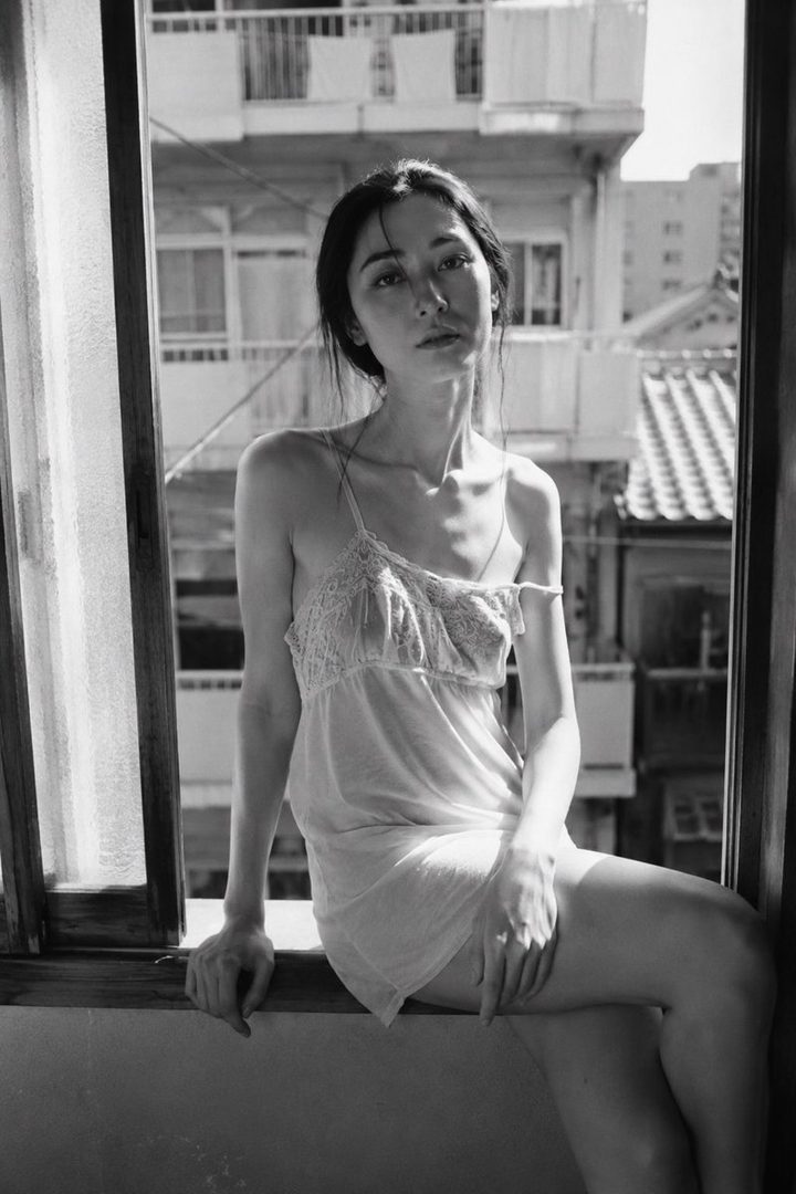 A black and white photorealistic portrait of a woman in a slip dress sitting by a window, looking directly at the viewer.