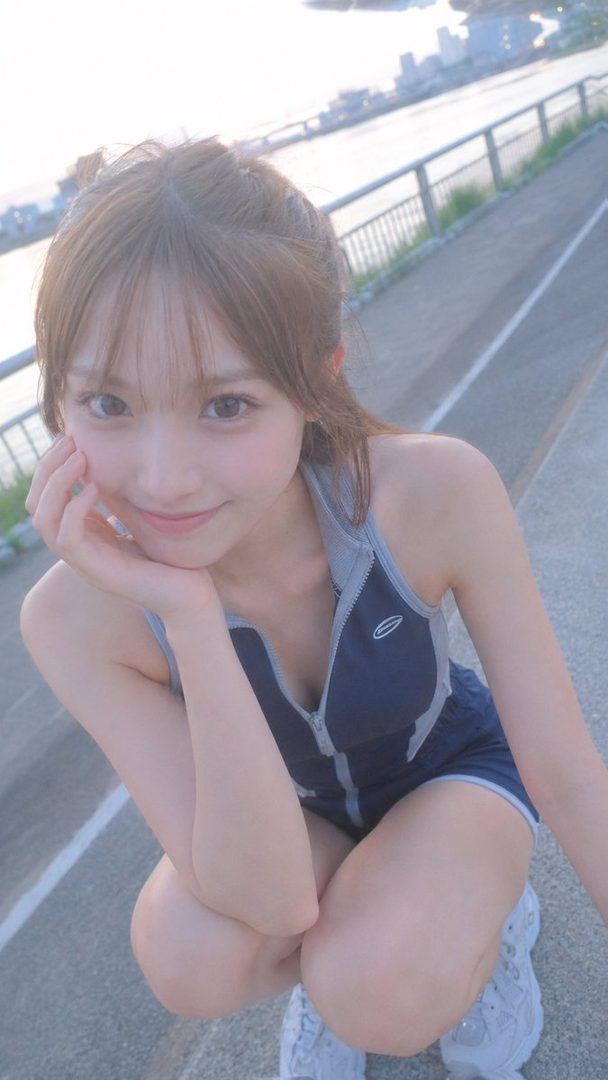 A cute East Asian woman in sportswear crouches outdoors, smiling at the camera.