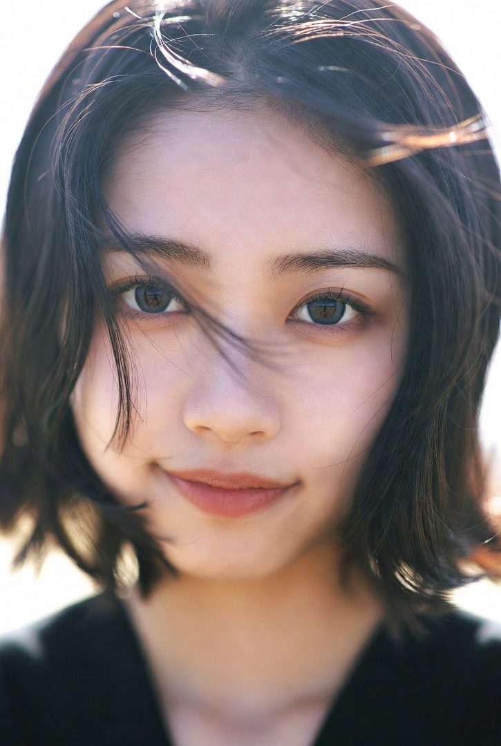 A close-up portrait of a young East Asian woman with short black hair, looking directly at the camera with a slight smile.