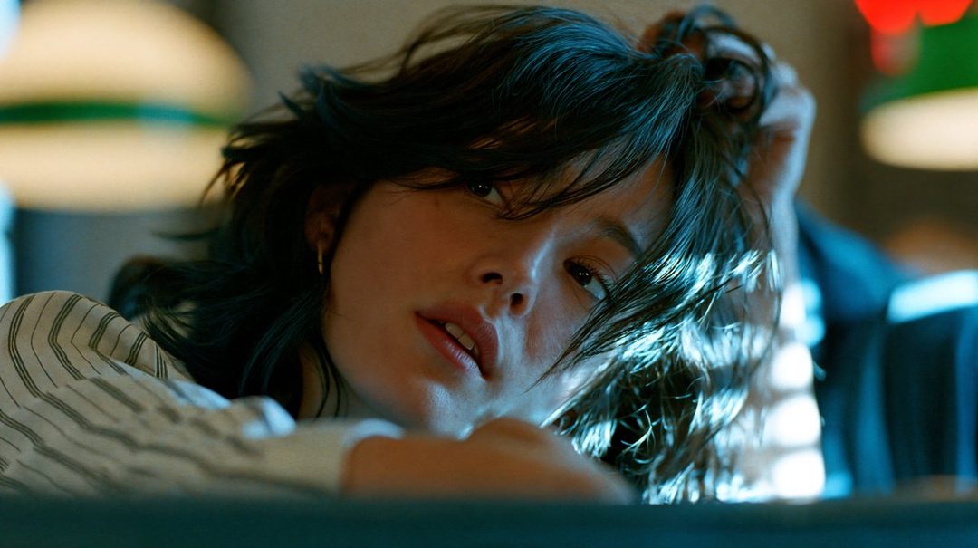 A photorealistic portrait of a young woman with dark hair, wearing a striped blouse, looking directly at the viewer with a dreamy expression.