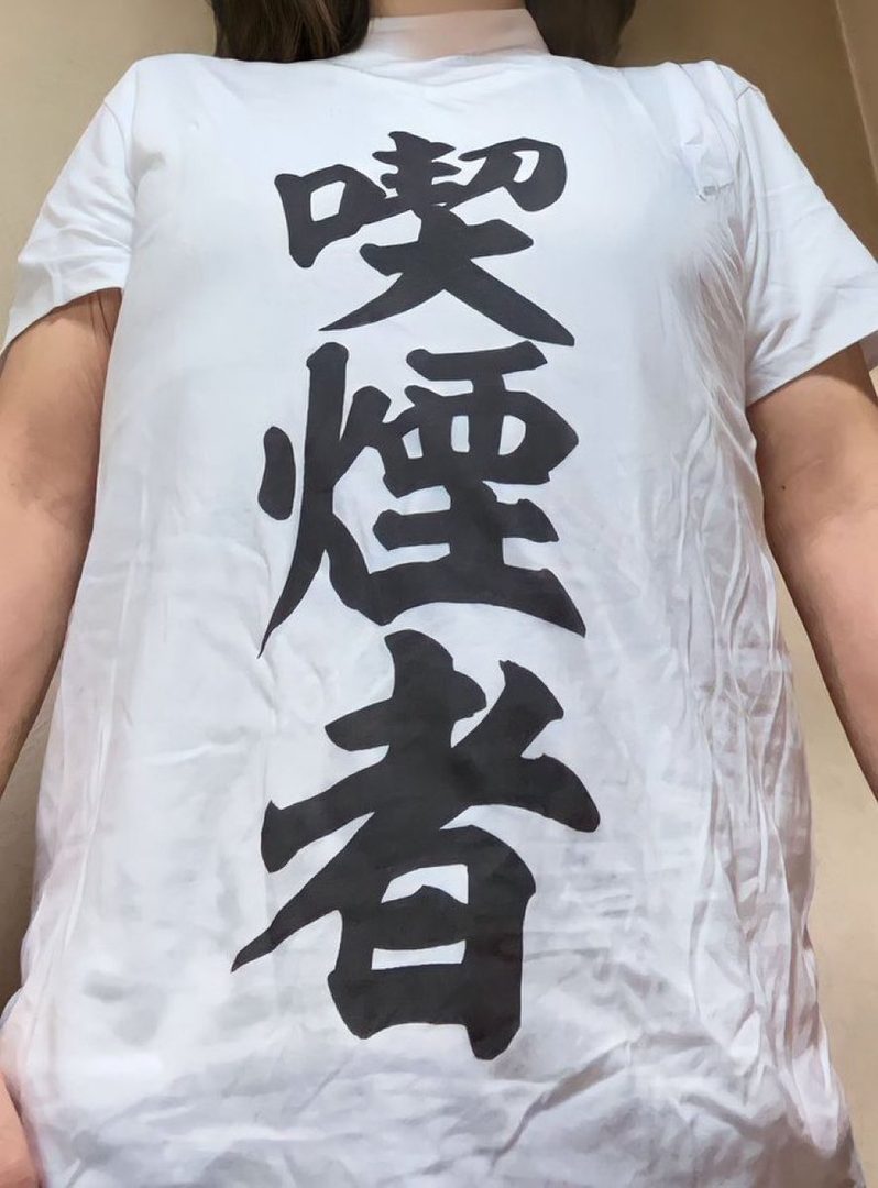 A person wearing a white t-shirt with large black Japanese characters on it.