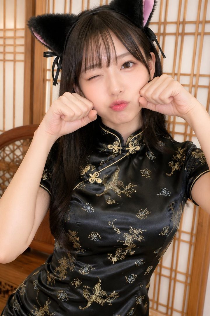 A young woman with black hair and cat ears winks and makes a cute face while wearing a black cheongsam dress.