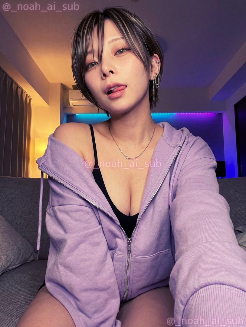 A woman with short brown hair and a purple hoodie takes a selfie indoors, sticking out her tongue playfully.