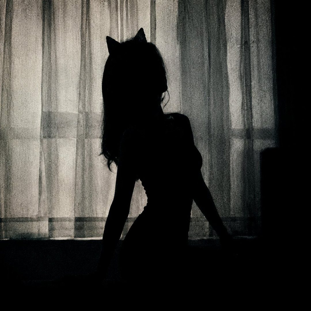 Silhouette of a woman with cat ears against a curtain, suggestive pose.