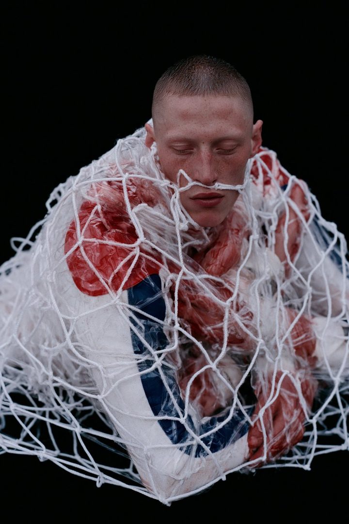 A man in a white and blue uniform is wrapped in netting, with red elements visible underneath.