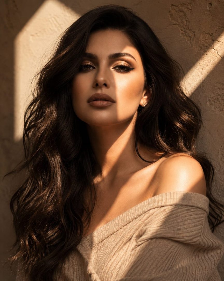 Photorealistic portrait of a woman with long dark wavy hair, wearing an off-shoulder beige knit top, bathed in warm golden-hour sunlight with geometric shadows.
