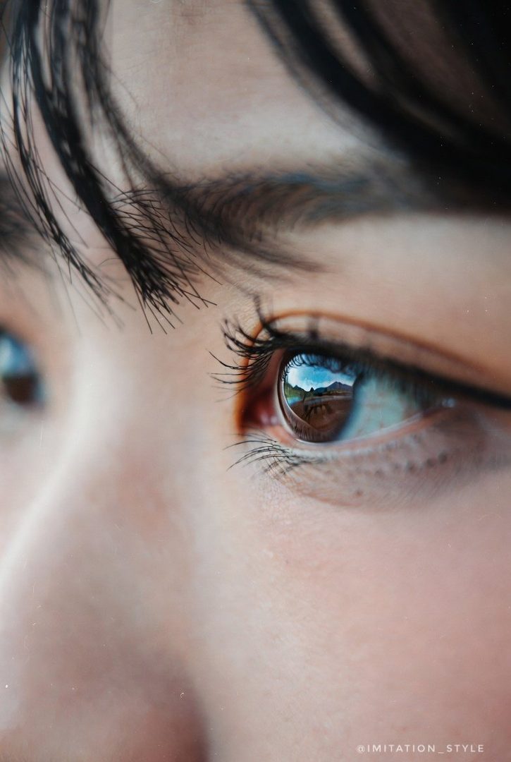 Close-up of a person's eyes, reflecting an outdoor landscape.
