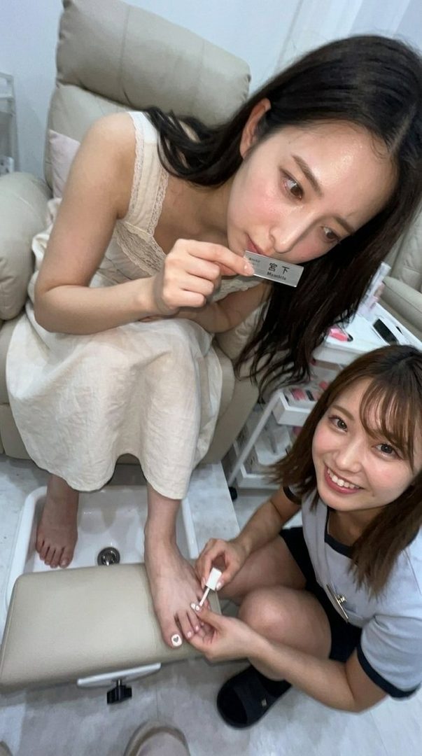 A woman receives a pedicure from a nail technician in a salon.
