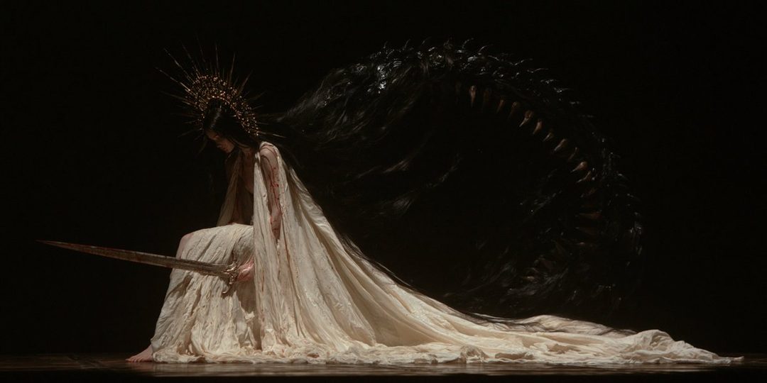 A woman in a flowing white dress and a spiky crown kneels with a sword, her dark hair cascading behind her like a monstrous wing.